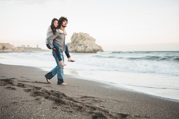 Young girl climbing on a man's back on the beach