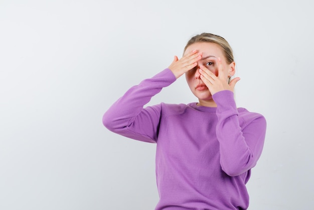 Young girl covering one of her eyes with her hands on white background