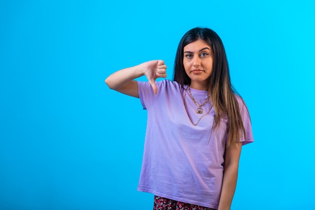 Young girl doing thumbs down sign with one hand. 