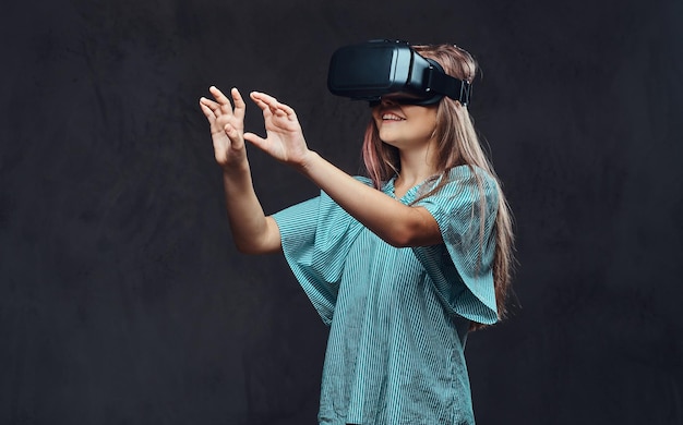 Young girl dressed casual using virtual reality glasses. Isolated on dark textured background.