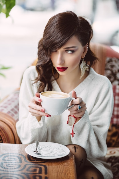 Free photo young girl drinking coffee in a trendy cafe