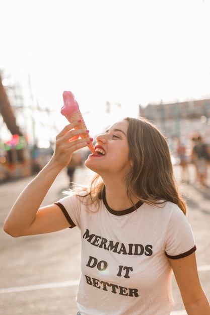 Free photo young girl eating ice cream in the amusement park