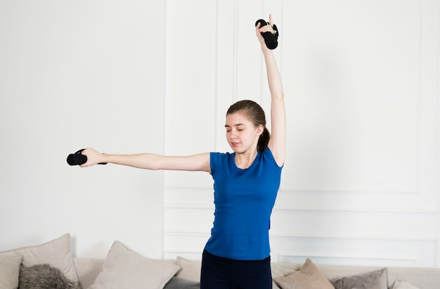 Young girl exercising with weights at home