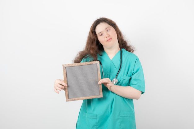 young girl in green uniform holding a frame.