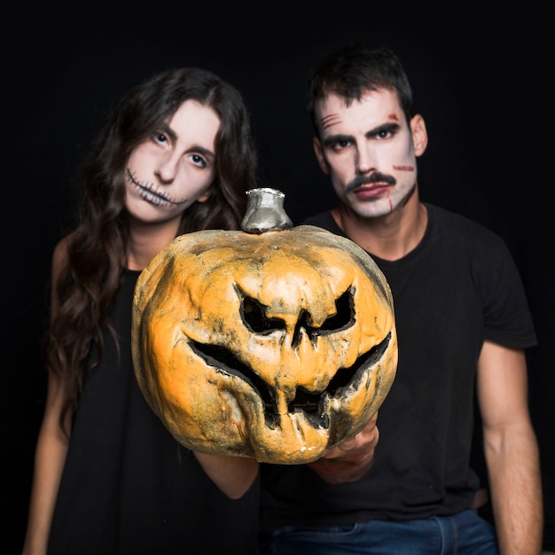 Free Photo young girl and guy holding creepy jack-o-lantern