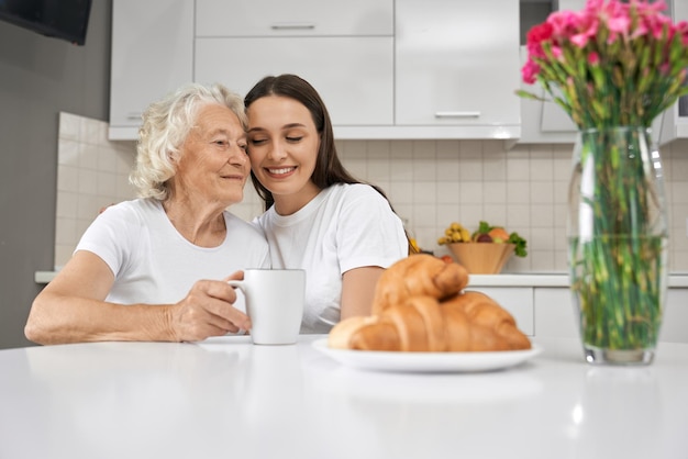 Young girl hugging grandmother in kitchen