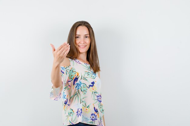 Young girl inviting to come in shirt, jeans and looking friendly , front view.