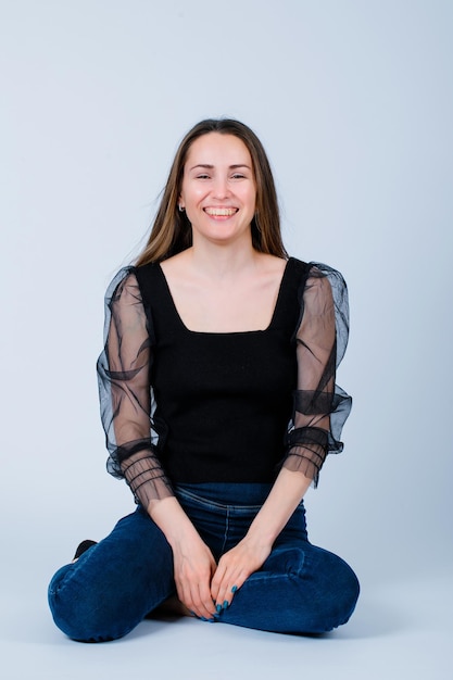 Young girl is laughing by sitting on floor on white background