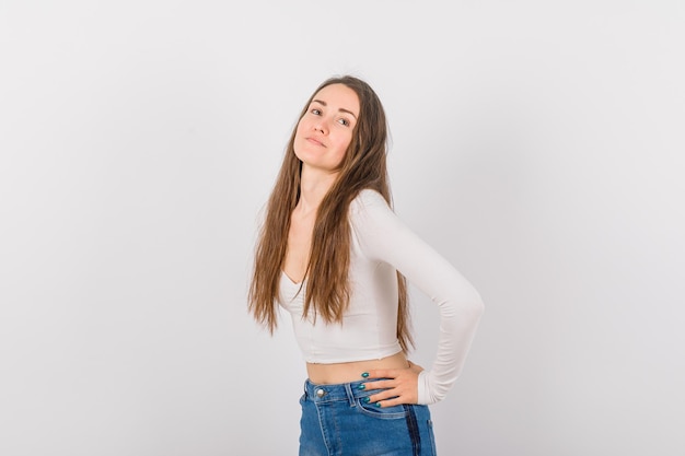 Young girl is looking away by putting hand on waist on white background