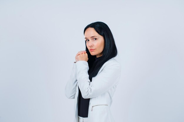 Young girl is looking at camera by holding together hands on white background