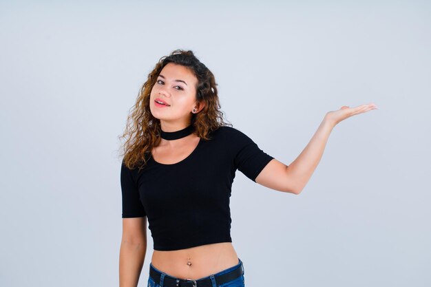 Young girl is looking at camera by pointing right with hand on white background