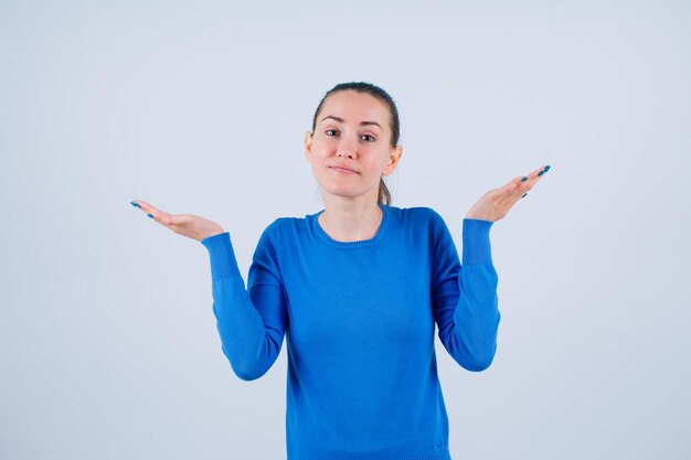 Young girl is looking at camera by raising up her hands on white background