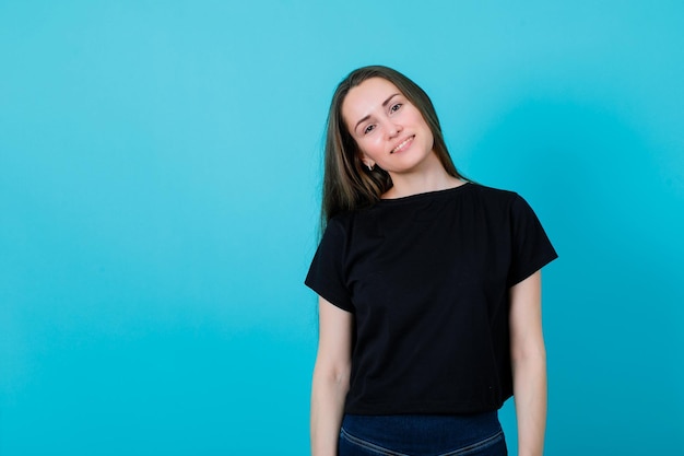 Young girl is looking at camera by smiling on blue background