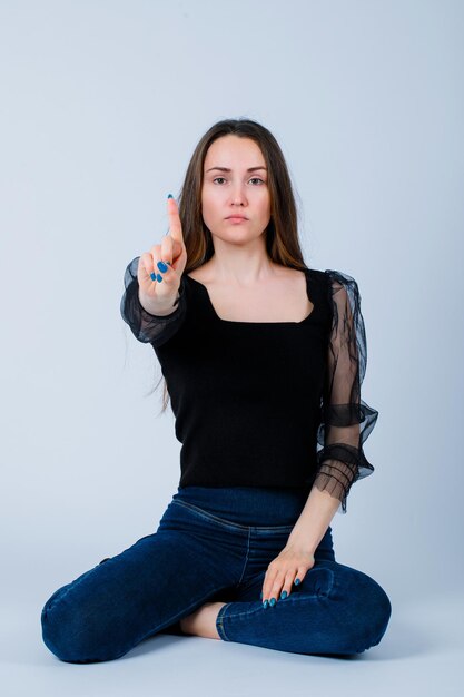 Young girl is showing a minute gesture by sitting on floor on white background