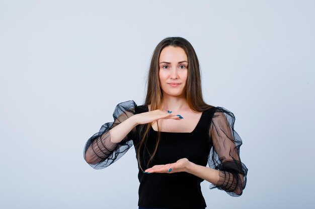 Young girl is showing size gesture by holding hands up and down on white background