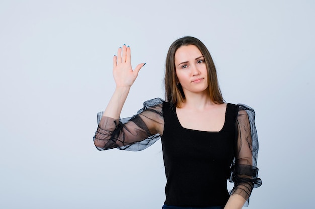 Young girl is showing stop gesture by raising up hand on white background