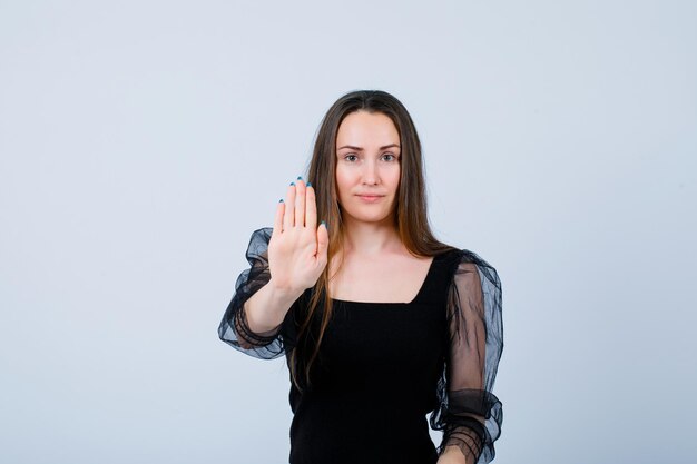 Young girl is showing stop gesture with hand on white background