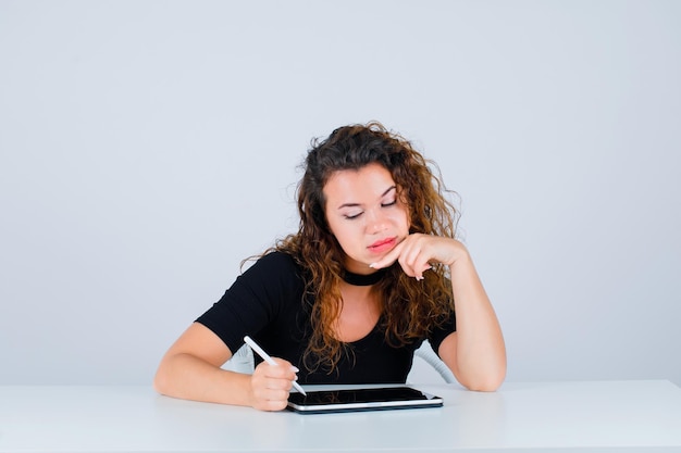 Free photo young girl is writing by putting hand on chin on white background