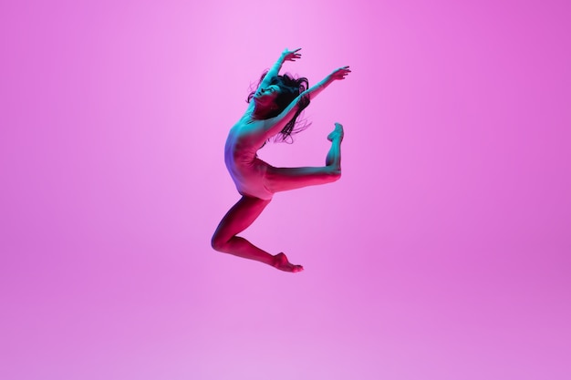 Free photo young girl jumping on pink wall