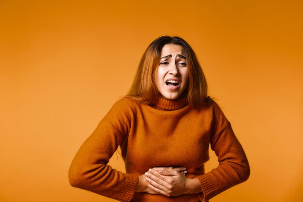 Young girl keeps for her stomach and feel pain standing 