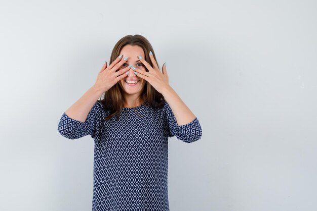 Young girl laughing and holding her eyes between her fingers on white background