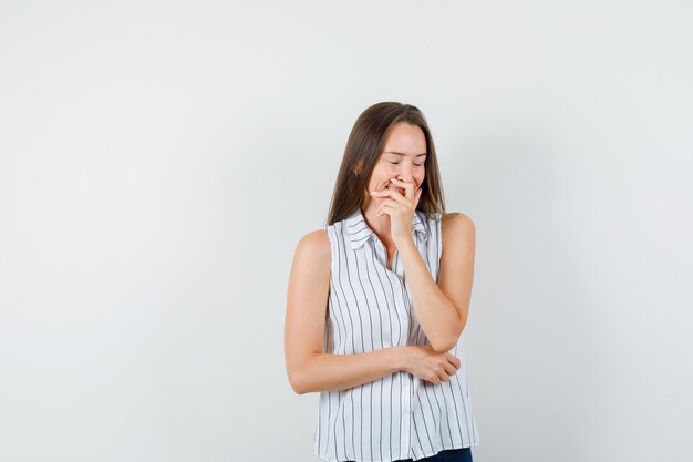 Young girl laughing with hand over mouth in t-shirt, jeans front view.