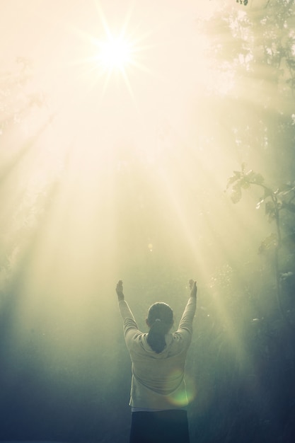 Free photo young girl meditate in the green forest with sunlight