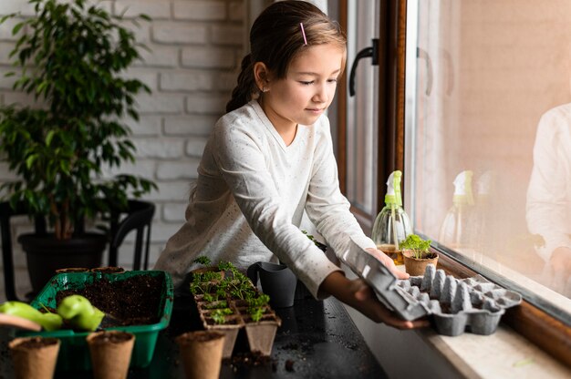 Young girl planting seeds by the window