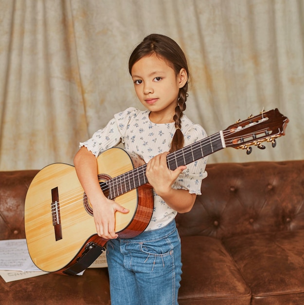 Young girl playing guitar at home