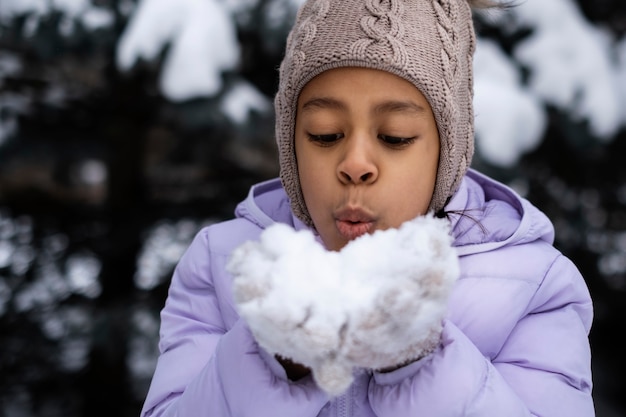 Young girl playing with snow outside on a winter day