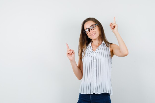 Young girl pointing up in t-shirt, jeans and looking cheery. front view.