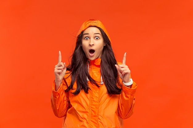 The young girl posing at  in autumn jacket isolated on red