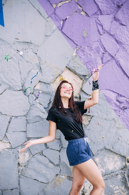 Young girl posing in front of painted stone wall