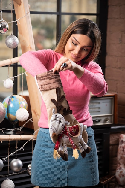 A young girl putting hand in a sock with Christmas deer . 