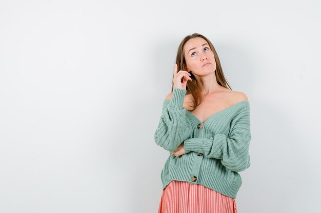 Young girl raising index finger in eureka gesture in knitwear, skirt and looking sensible. front view.