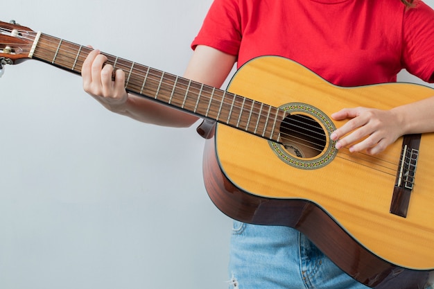 Young girl in red shirt holding an acoustic guitar