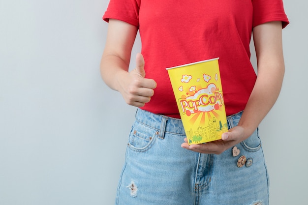 Free Photo young girl in red shirt holding a bucket of popcorns