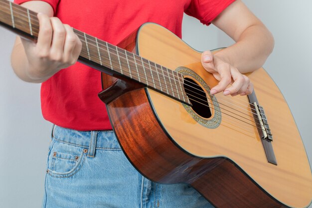 Young girl in red shirt holding a wooden guitar