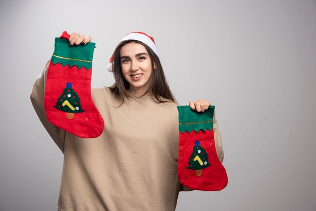 Free Photo young girl in santa's hat holding two christmas socks .