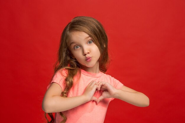 Young girl sending a kiss and making heart sign with hands