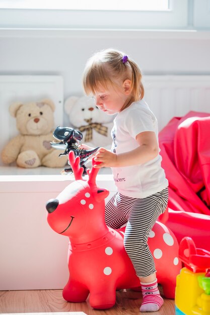 Young girl sitting on red deer toy