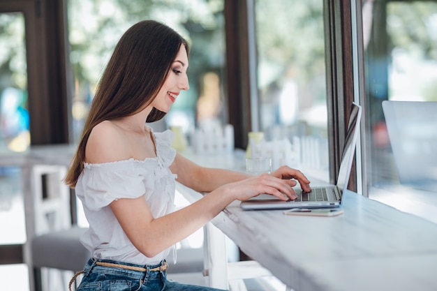 Young girl smiling typing on a laptop next