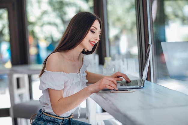 Young girl smiling typing on a laptop next