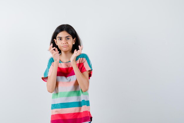 Young girl spreading palms out in colorful striped t-shirt and looking cute , front view.