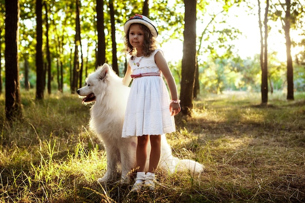 Young girl walking playing with dog in park at sunset