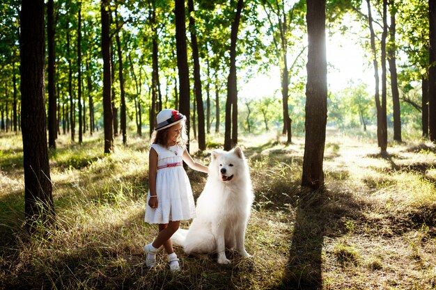 Young girl walking, playing with dog in park at sunset.