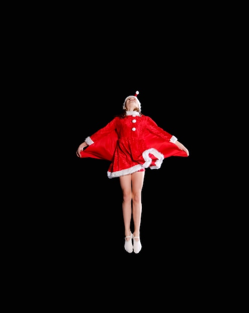 A young girl wearing a Santa's costume is flying. Christmas time, childhood, fairy tale.