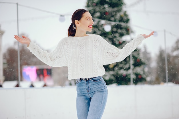 Young girl in a white sweater standing in a winter park