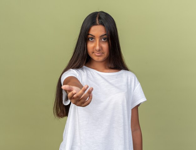 Young girl in white t-shirt looking at camera making come here gesture with hand smiling friendly 