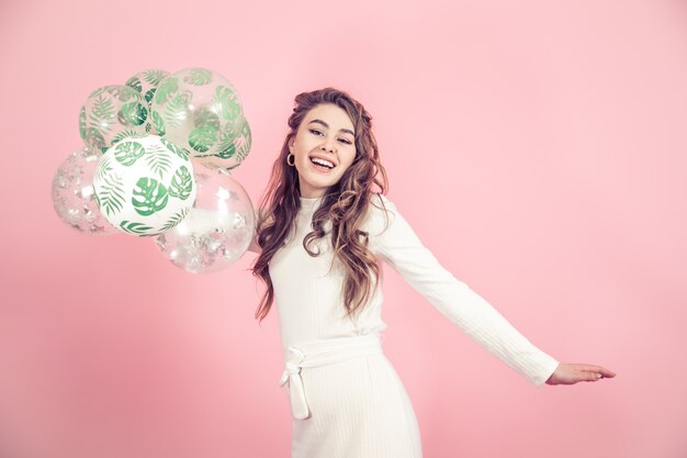 Young girl with balloons on a colored wall